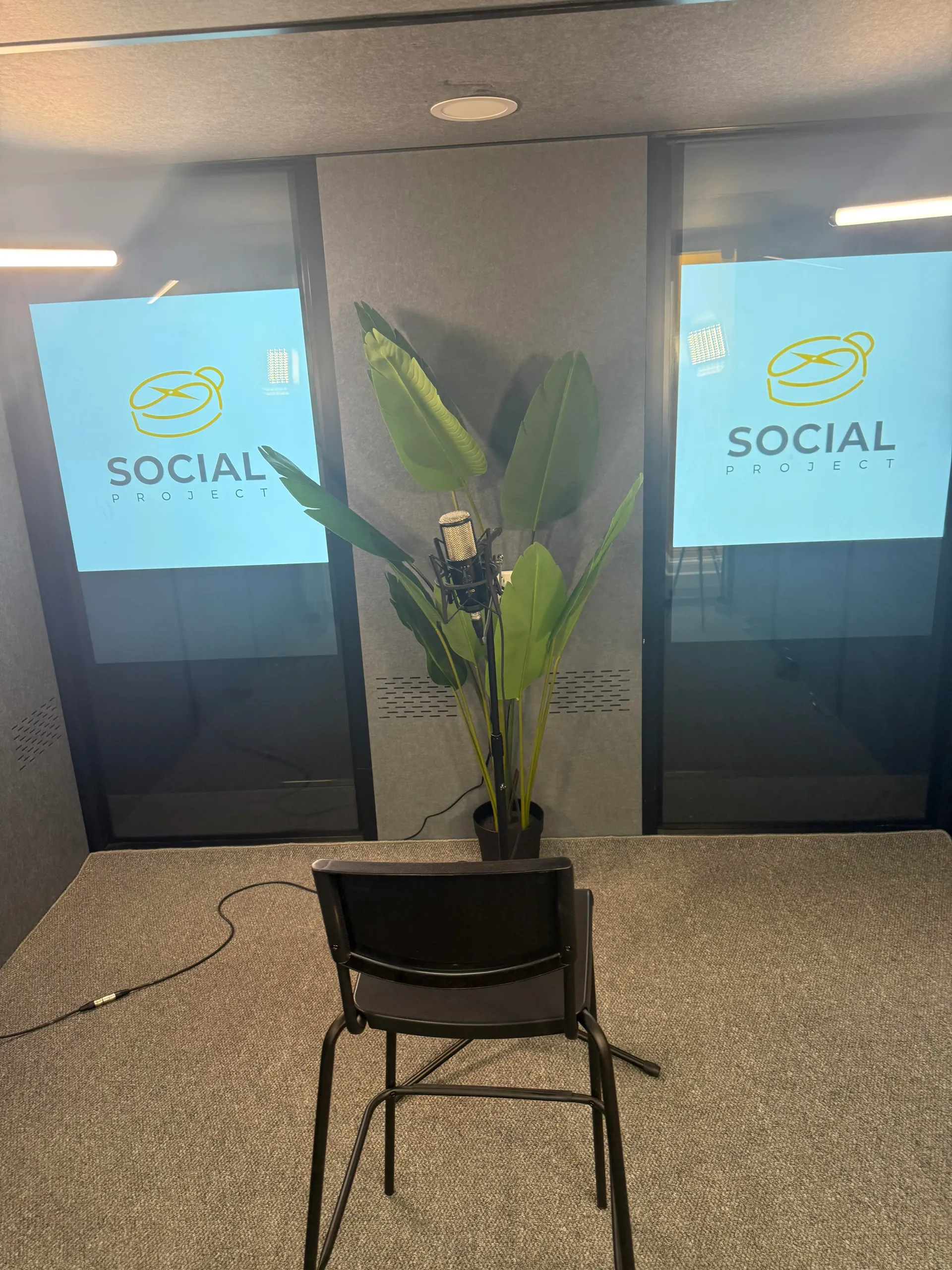 Podcast booth with backlit Social Project branding panels